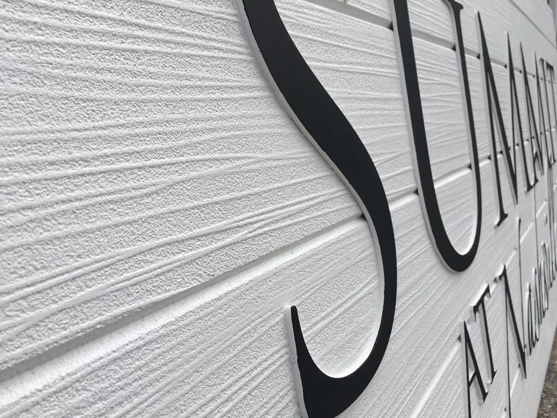 Routed HDU panel — close view of carved woodgrain texture and raised letters.