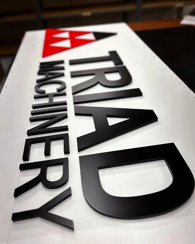 TRIAD Machinery black red and white dimensional sign