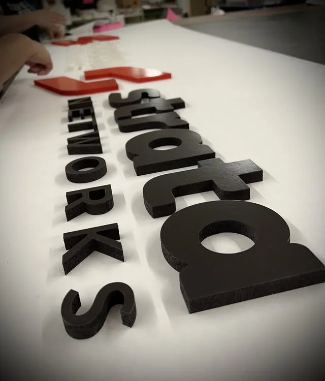 Black and red layered acrylic logo components in production