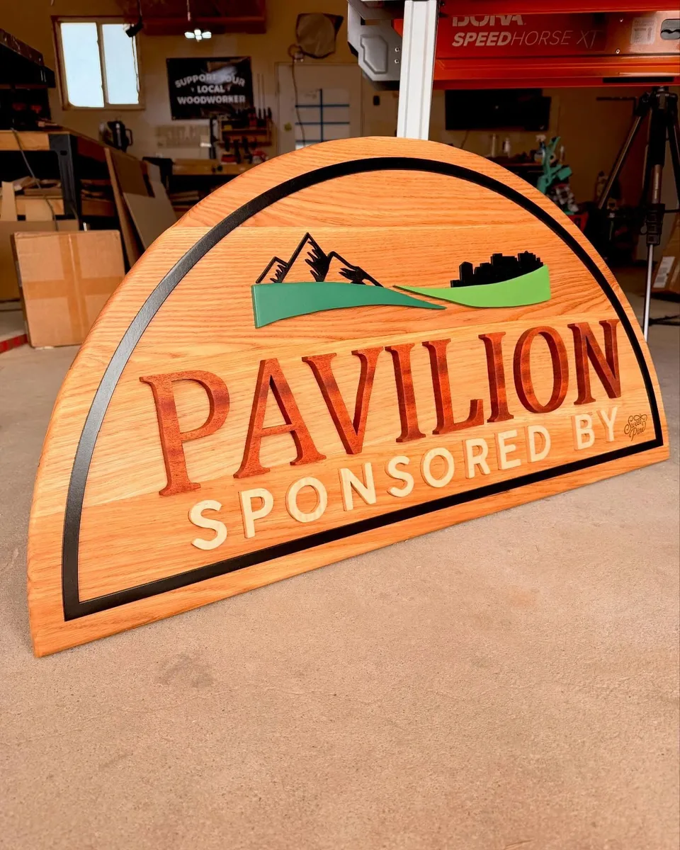 Pavilion Sponsor Sign — Custom-shaped dimensional sign with raised lettering and layered graphics.