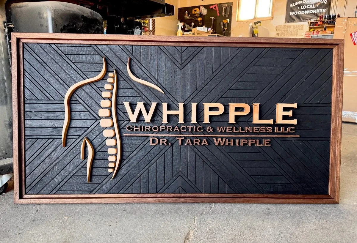 Whipple Chiropractic & Wellness — Dimensional business sign with a dark textured face, raised metallic-look lettering and a framed panel.