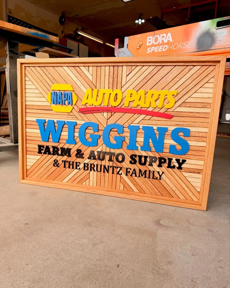Wiggins Farm & Auto Supply — Layered business sign photographed in the shop before delivery.
