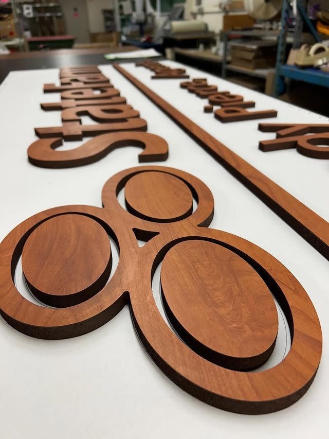 Brown woodgrain dimensional letters and circular logo pieces