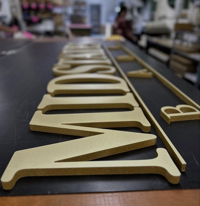 Cream dimensional letters lined up on a production table