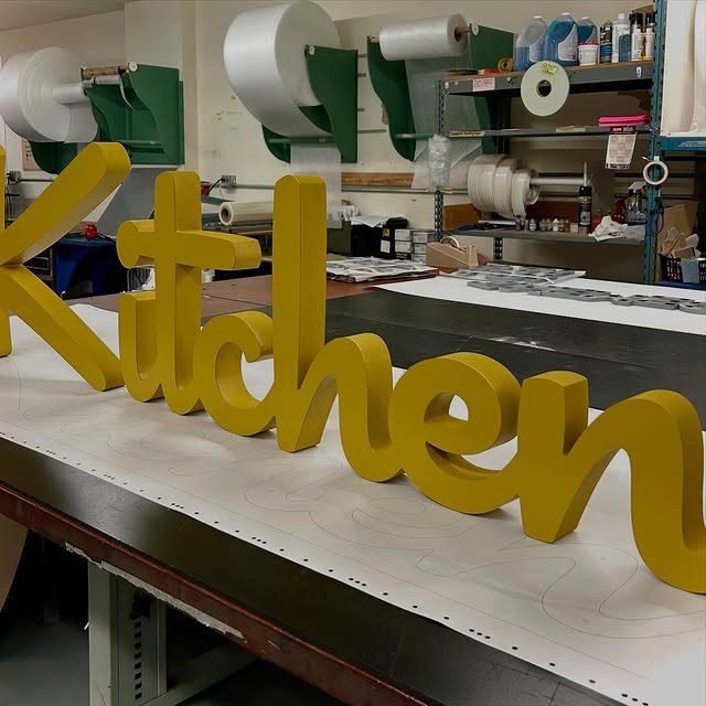 Gold dimensional letters arranged on a sign-shop workbench