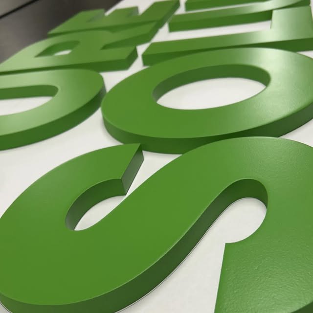 Green dimensional logo letters in a close production view