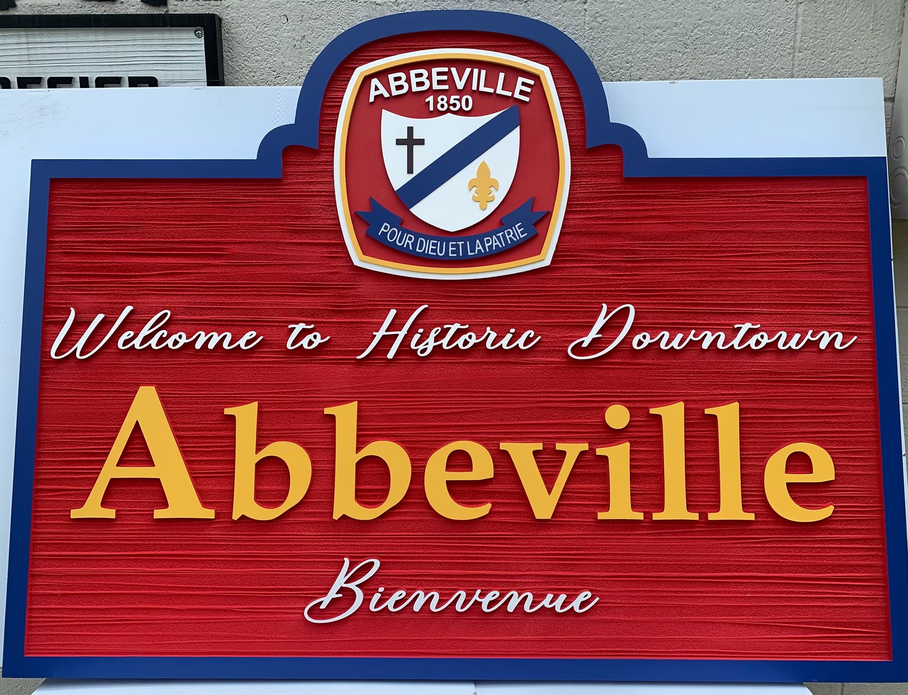 Large carved-style downtown welcome sign with raised gold lettering