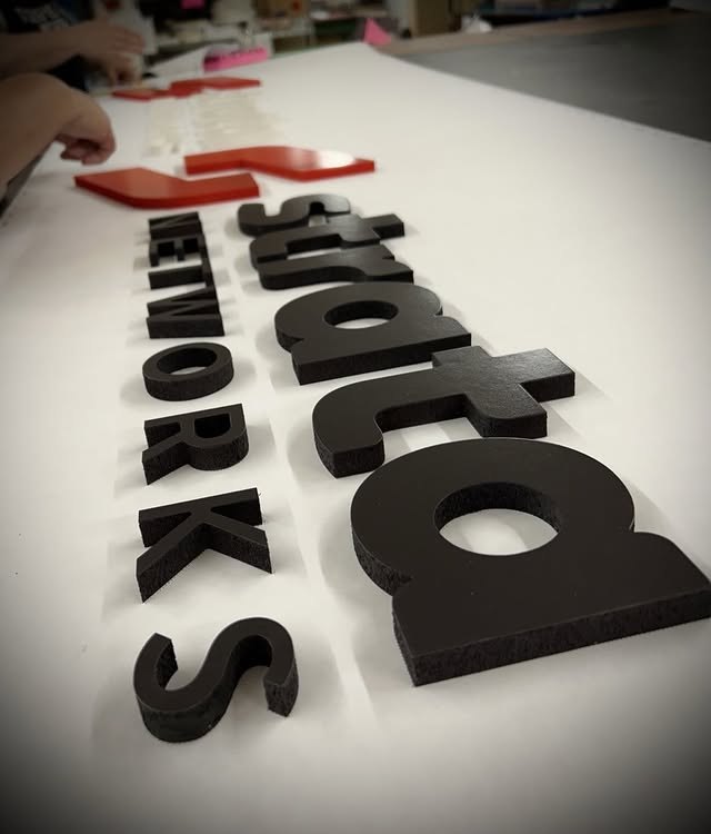 Black and red layered acrylic logo components in production