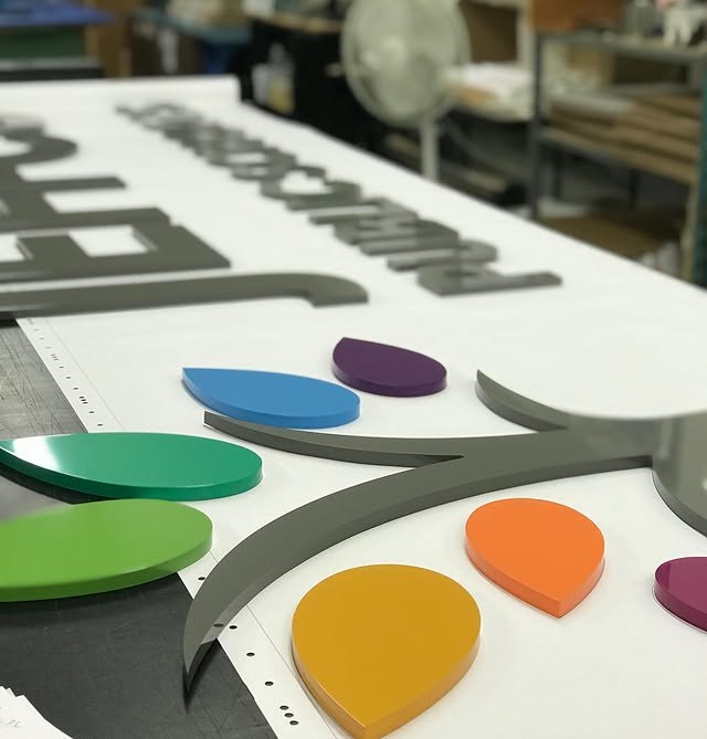 Multicolor layered acrylic logo parts on a white production panel