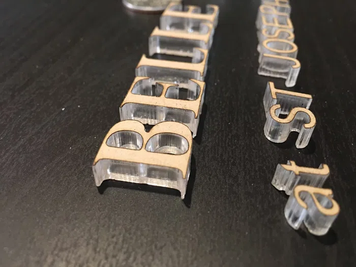 Clear acrylic dimensional letters arranged on a worktable