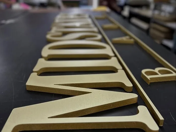 Cream dimensional letters lined up on a production table