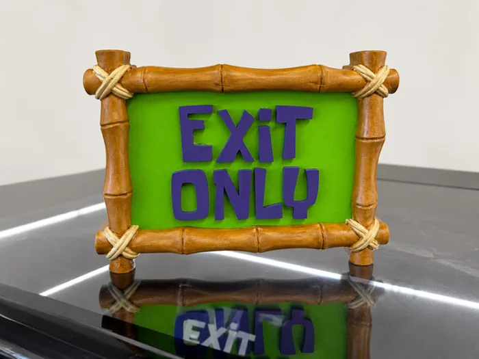 Completed Exit Only dimensional sign with purple letters and bamboo-style frame in the shop