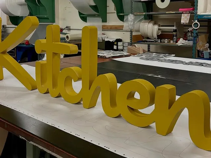 Gold dimensional letters arranged on a sign-shop workbench