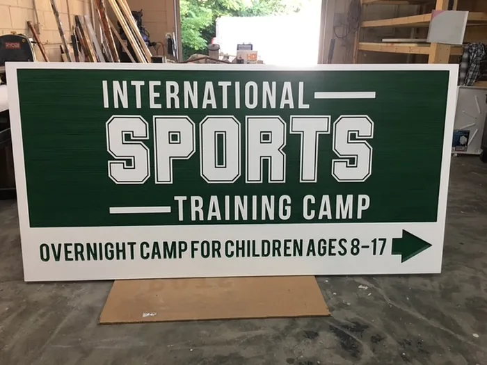 Green International Sports Training Camp directional sign with white raised letters