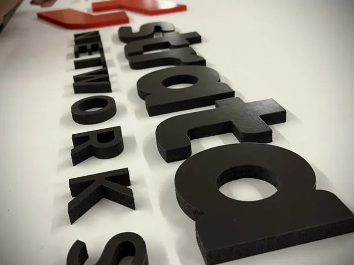 Black and red layered acrylic logo components in production