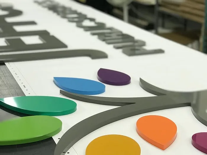 Multicolor layered acrylic logo parts on a white production panel