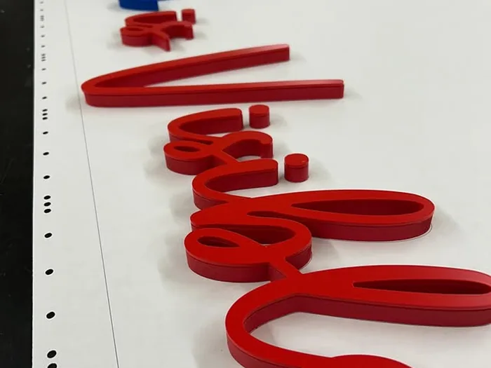 Red script acrylic letters laid out for a custom wall sign