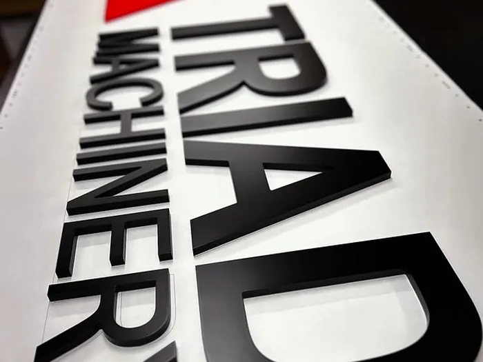 TRIAD Machinery black red and white dimensional sign