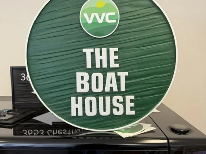 Round green VVC The Boat House sign with woodgrain texture