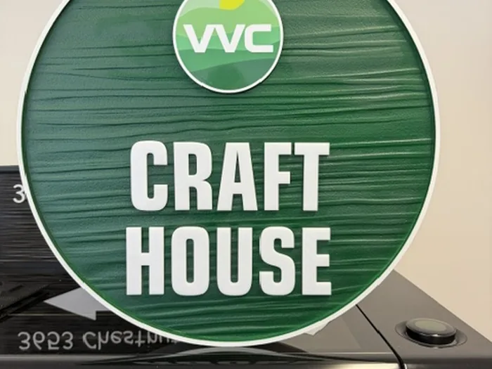 Round green VVC Craft House sign with woodgrain texture