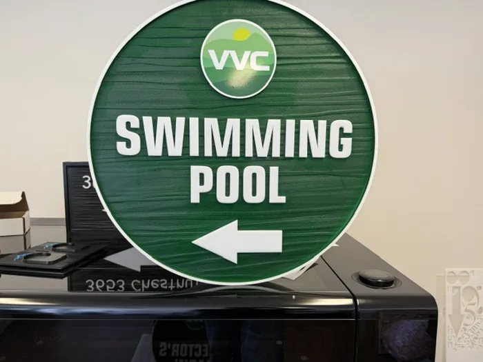 Round green VVC Swimming Pool directional sign with left arrow