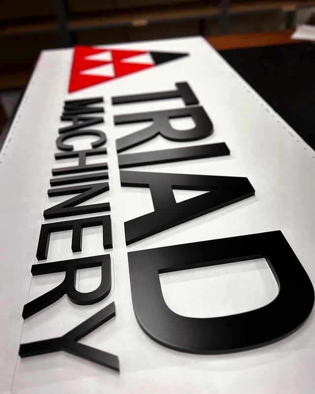 TRIAD Machinery black red and white dimensional sign